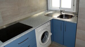 A compact kitchen with a built-in stove, a washing machine, and a sink. - Minimalist center loft (Córdoba)