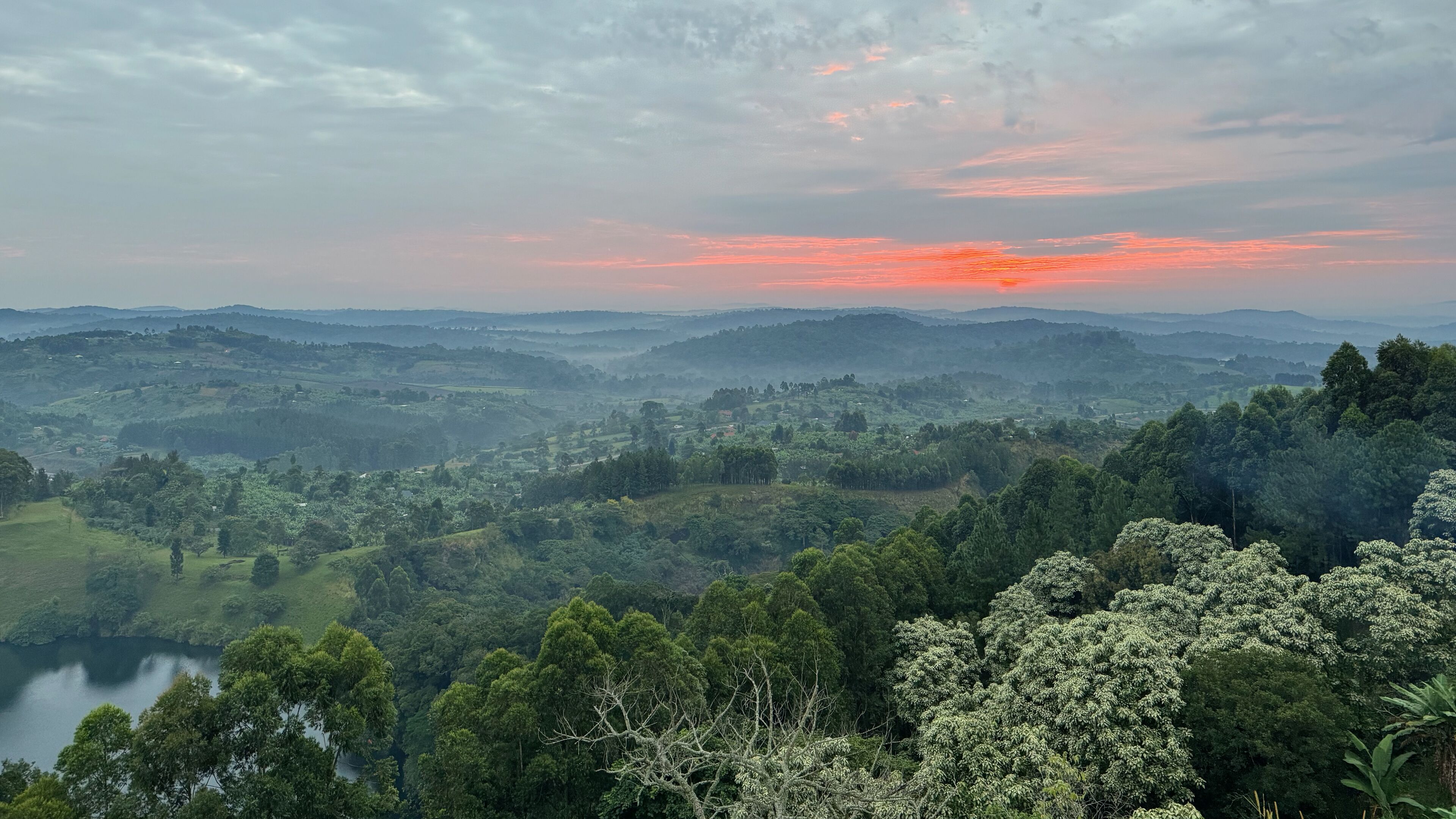 A panoramic view of a lush, green landscape with rolling hills and a river in the foreground.