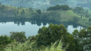 A panoramic view of a lake surrounded by lush green hills and dense forests.