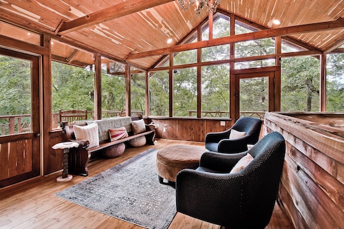 Escape to Whispering Hollow, a peaceful retreat near Eureka Springs with a dreamy glass room, cozy indoor spaces, and a brand-new hot tub for unwinding under the trees and surrounded by nature.
