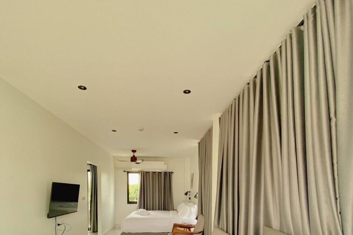 A hotel room with a large bed, a smaller bed, a desk, and a TV.