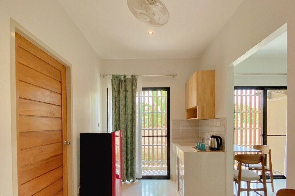 A compact kitchen with a refrigerator, a coffee maker, and a dining area with chairs.
