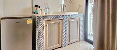 A modern bathroom with a built-in sink, mirror, and a small refrigerator.