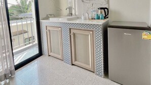 A modern kitchen with a built-in refrigerator, a sink, and a window overlooking a balcony. - Calamint Residence Hotel  (Chumphon)