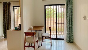 A spacious room with a dining area, a small kitchen counter, and a sliding glass door leading to a balcony. - Calamint Residence Hotel  (Chumphon)
