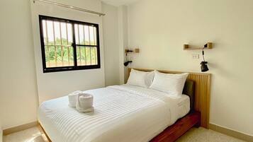 Une chambre à coucher avec un lit, un ventilateur de plafond, une fenêtre et une table de chevet avec une lampe.
