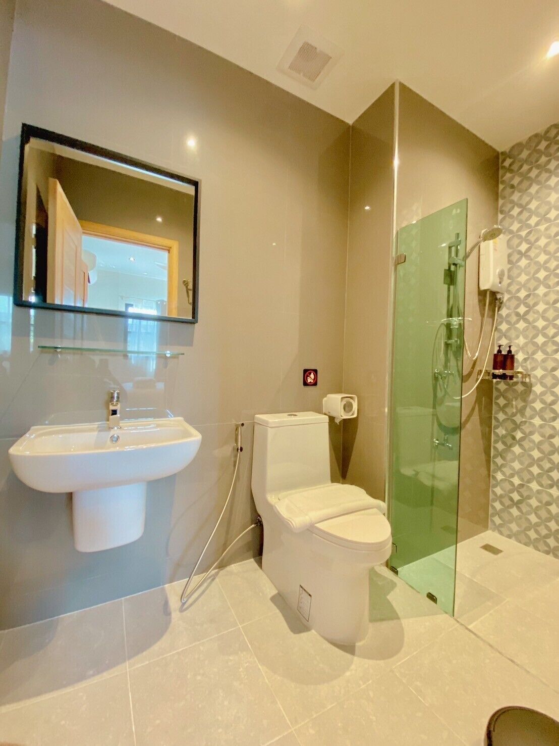 Un baño moderno con ducha acristalada, lavabo blanco y un inodoro.