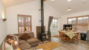 A cozy living room with a fireplace, a sofa, a dining area with a table and chairs, and a large window with blinds.