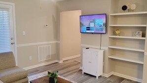 Un salon avec un téléviseur fixé au mur, un meuble blanc et un canapé beige.