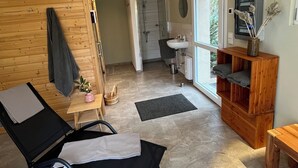 Una habitación amplia con un gran ventanal, una pared de madera, una silla negra, un estante de madera y una lámpara en el techo.