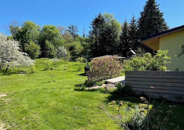 A well-maintained garden with a variety of flowering plants and trees, a wooden bench, and a small shed. - Vacation apartment at Düstersee with a terrace and sauna in your own backyard (Temmen-Ringenwalde)