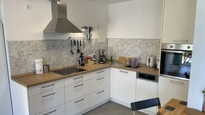 Una cocina moderna con armarios blancos, encimera de madera y horno empotrado.