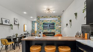 A modern kitchen with a central island, bar stools, and a dining area with chairs.