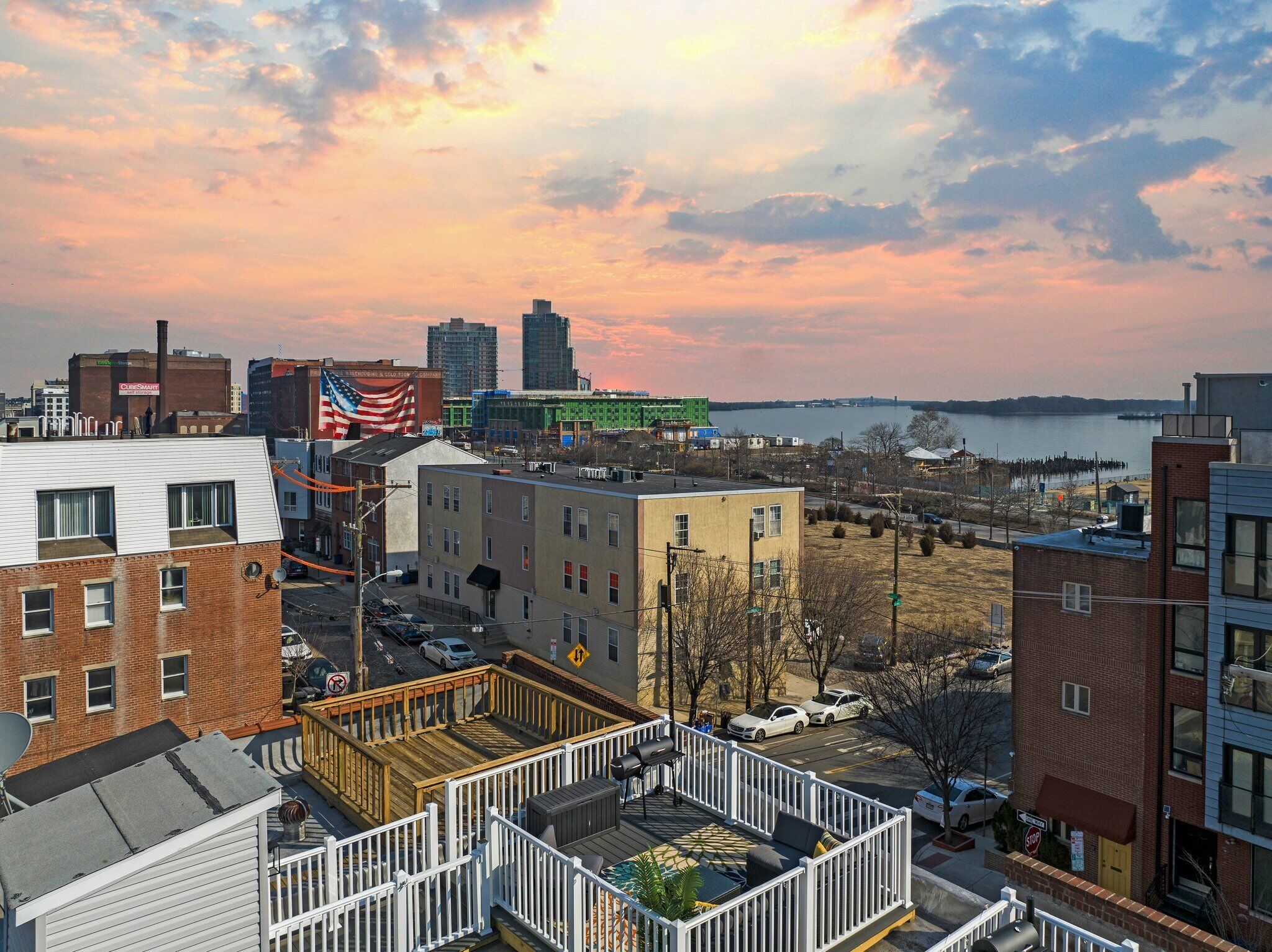 A cityscape with a waterfront view, including a dock and a large building with an American flag.
