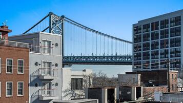 A modern building with a large glass facade, a prominent bridge in the background, and a mix of brick and concrete structures nearby.