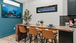 A modern kitchen with a wooden island, bar stools, a large aquarium, and a built-in microwave.
