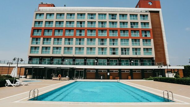 Un hotel con piscina, varios pisos y un diseño arquitectónico moderno.