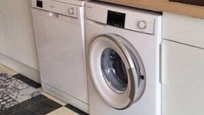 A compact kitchen with a washing machine, a sink, and a wooden countertop.