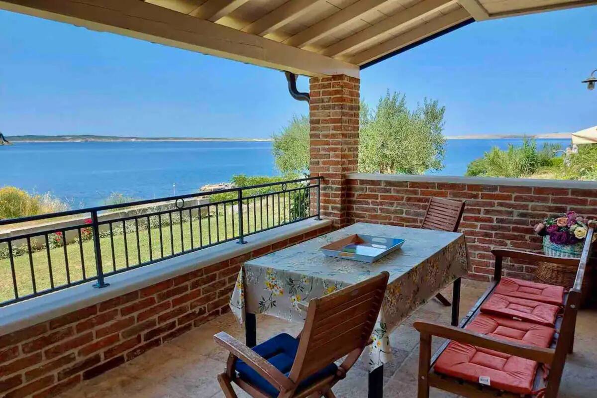A covered patio with a table and chairs, overlooking a body of water.
