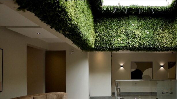 Un interior moderno con una pared verde, un sofá, una mesita y una barandilla de cristal.