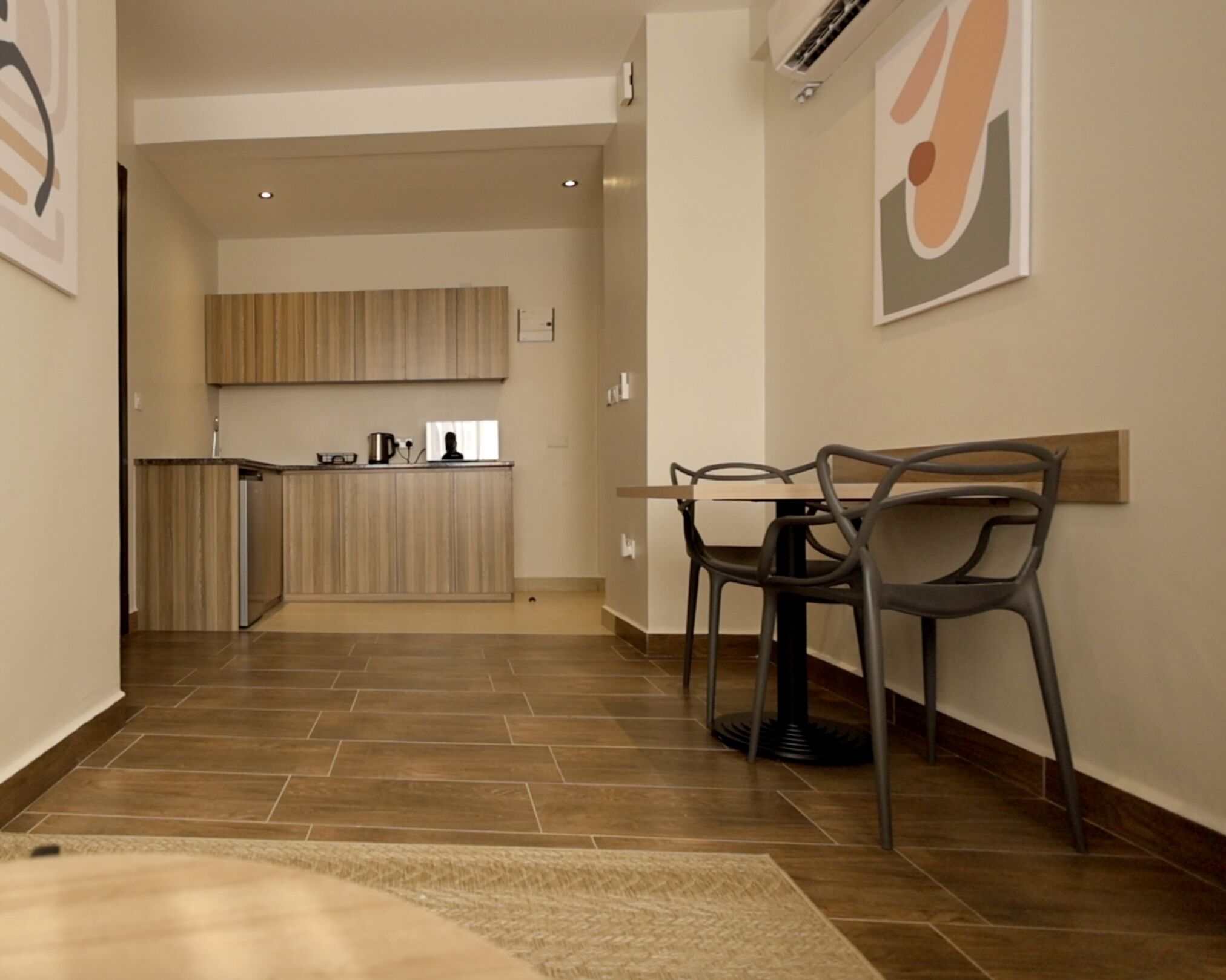 Una cocina moderna con armarios de madera, un comedor con dos sillas y una alfombra en el suelo.