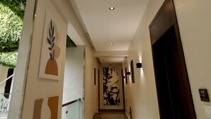 Un pasillo moderno con una puerta de cristal, una puerta de madera y una lámpara fijada a la pared.