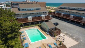 A hotel with a swimming pool, outdoor seating, and a view of the beach. - Oceanblock Townhome Mid Town with Pool (Ocean City)
