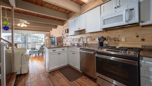 A kitchen with wooden floors, white cabinets, a stainless steel stove, and a microwave. - Oceanblock Townhome Mid Town with Pool (Ocean City)