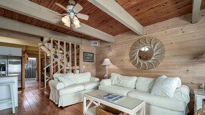 A spacious living area with a wooden ceiling, white sofas, a glass coffee table, and a decorative mirror. - Oceanblock Townhome Mid Town with Pool (Ocean City)