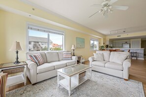 A living room with two sofas, a coffee table, and a dining area with a kitchen in the background.