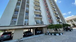 A multi-story residential building with balconies, a parking area, and a clear sky. - Mulliner Towers (Lagos)