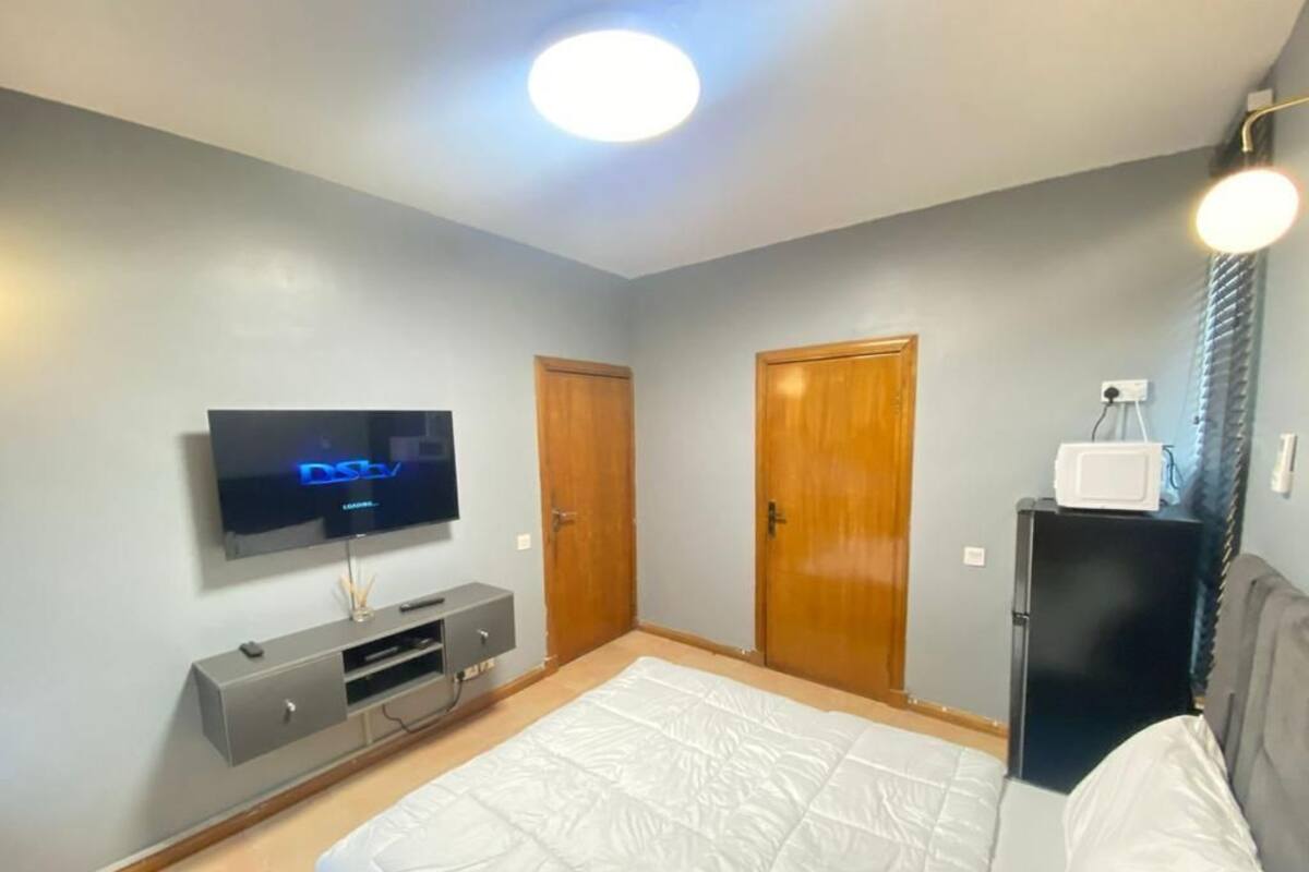 A bedroom with a bed, a TV, a wardrobe, and a small table.