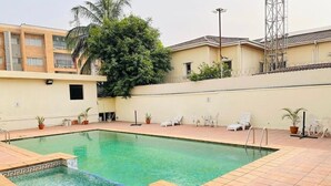 A rectangular swimming pool with tiled edges, surrounded by a tiled patio area. - Mulliner Towers (Lagos)