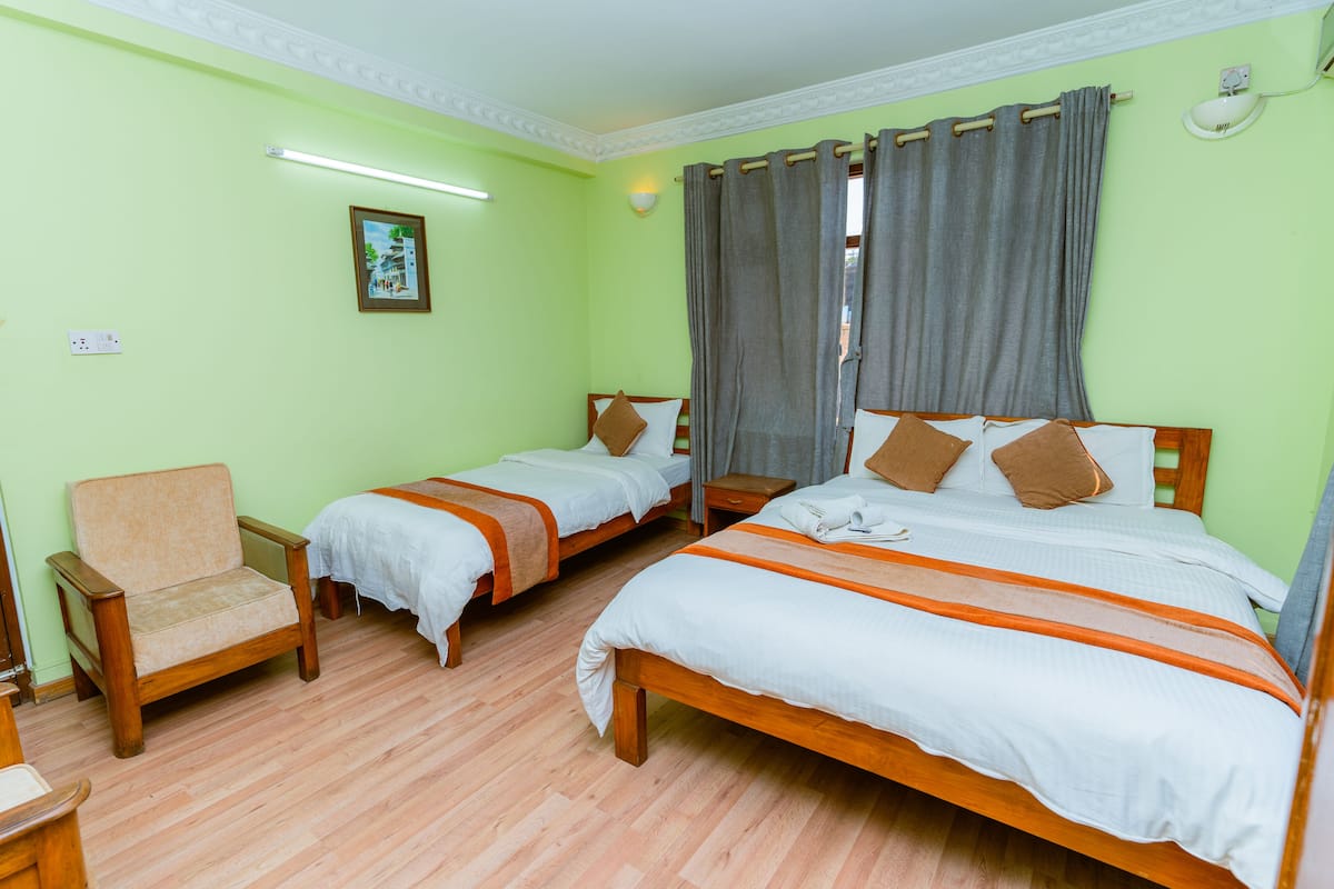 A hotel room with two single beds, a wooden chair, and a small table.