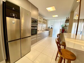 A modern kitchen with stainless steel appliances, a dining area with a wooden table and chairs, and a view of the living area.