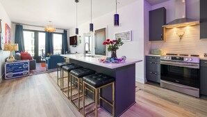 A modern kitchen with a central island, bar stools, a built-in oven, and pendant lighting. - Midtown Pool Condo · 2BR Sleeps 6 · Honky Tonk (Nashville)