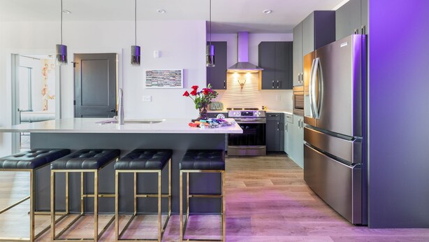 A modern kitchen with a central island, bar stools, stainless steel appliances, pendant lighting, and a view of the adjacent living area. - Midtown Pool Condo · 2BR Sleeps 6 · Honky Tonk (Nashville)