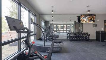 A gym with treadmills, stationary bikes, and dumbbells.