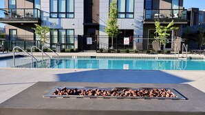 A modern building with a swimming pool, outdoor seating, and a fire pit area.
