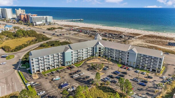 A hotel with a central courtyard, parking lot, and beachfront view. - 🌴  🌞Walk to Beach | Prime Location | 2BR Grand Caribbean 115🌞🌴 (Orange Beach)