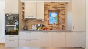 A modern kitchen with a built-in oven, microwave, and a window with a view of the sky.