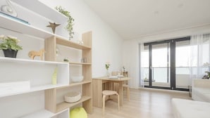 Una sala de estar moderna con piso de madera, muebles blancos y un ventanal con vistas.