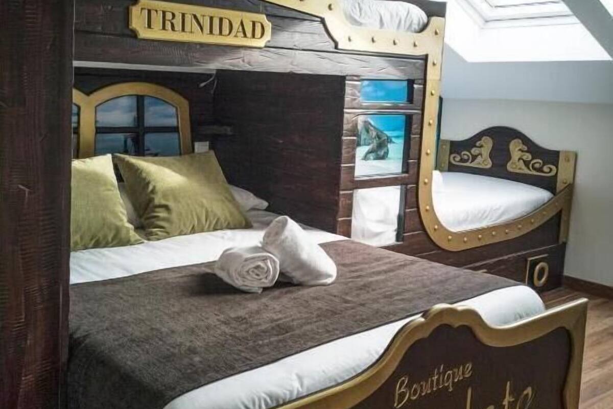 Quarto com uma cama identificada como 'TRINIDAD' e 'Boutique Chocolate Hostel'.