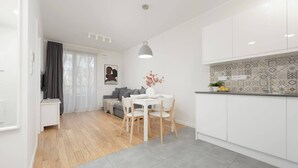 Una cocina moderna con armarios blancos, una lámpara colgante gris y un salpicadero con diseño.