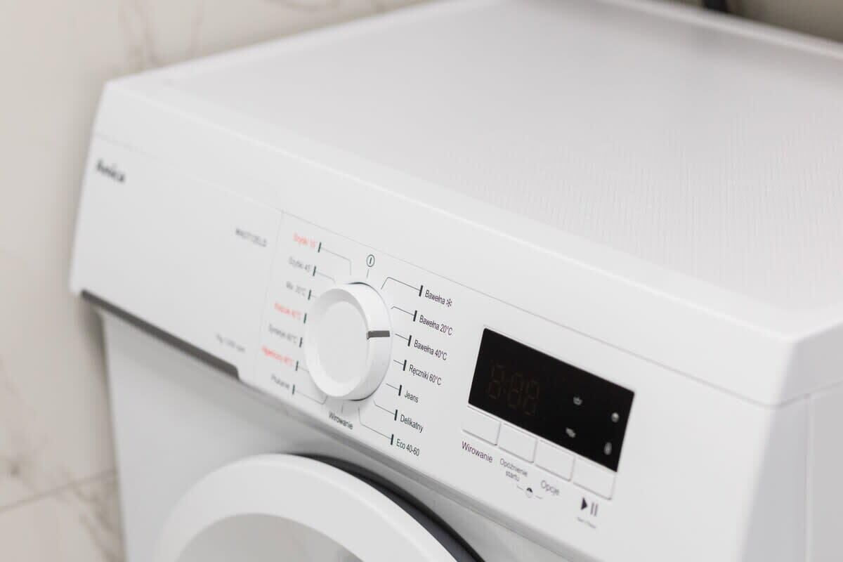 A front view of a white washing machine with a digital display and a control knob.
