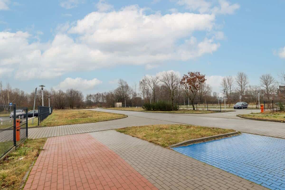 A paved pathway leading to a swimming pool with a fenced area on one side.