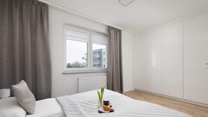 A modern bedroom with a bed, a window, and a wardrobe.