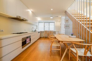 Eine moderne Küche mit weißen Schränken, einem Holzespeisetisch und einer Treppe mit Metallgeländern.