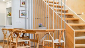 Una scala in legno dal design minimalista, un'area pranzo con tavolo e sedie in legno e una piccola pianta in vaso sul tavolo.