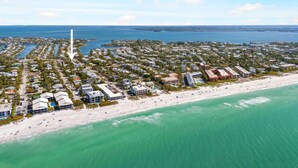 Vista aérea de una zona residencial costera con playa, casas y un faro.